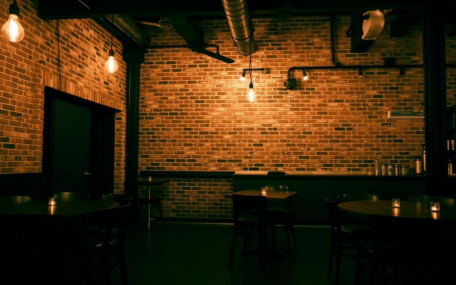 Industrial modern restaurant interior in New Haven Connecticut with exposed brick walls, blackened steel bar, and edison lighting